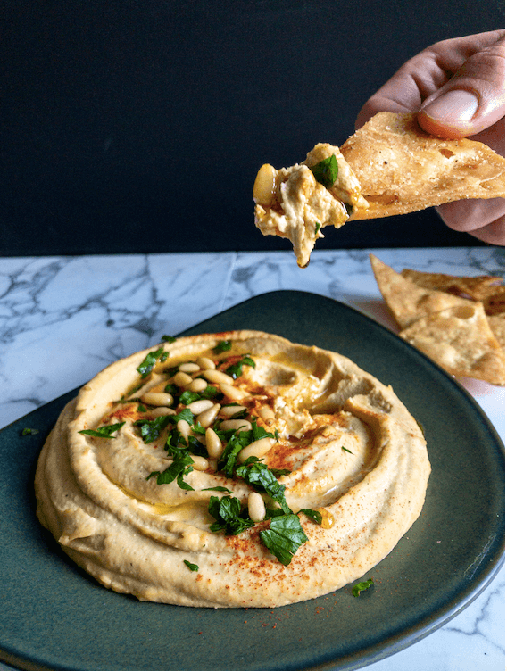 hummus on plate with chip dipped above