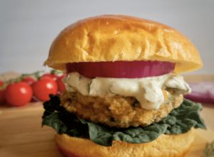 Chicken burger with spinach and feta on a bun with garnishes