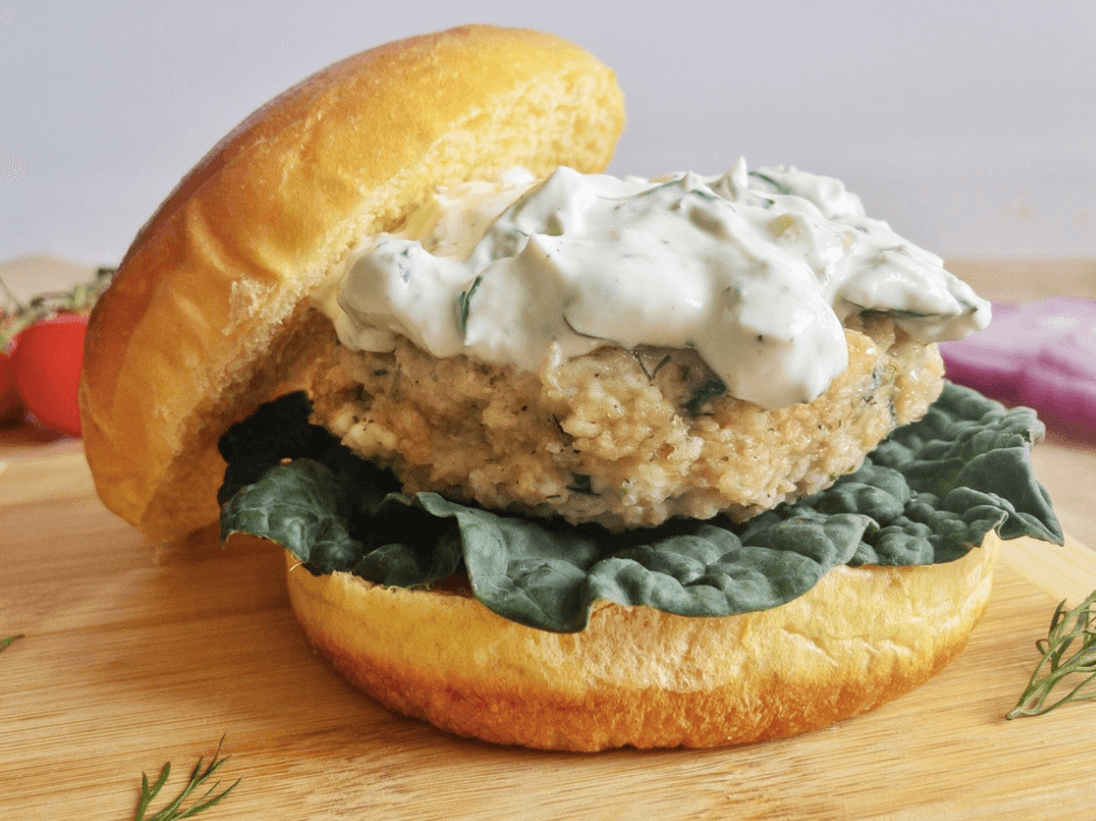 bun on side of chicken burger with tzatziki sauce