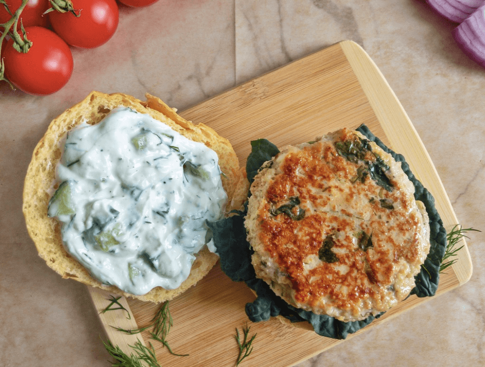 open burger patty on bun with tzatziki sauce