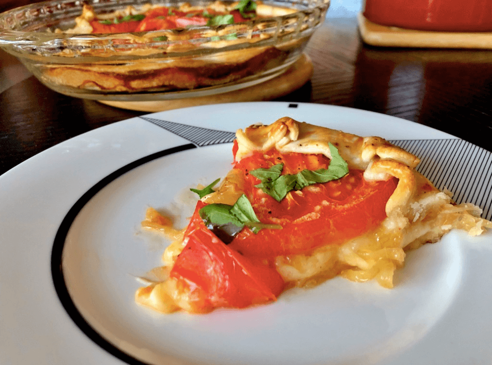 a slice of tart with cheese , caramelized onions and tomato
