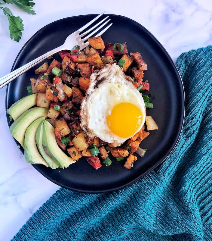 plated breakfast with egg served on top of potatoes