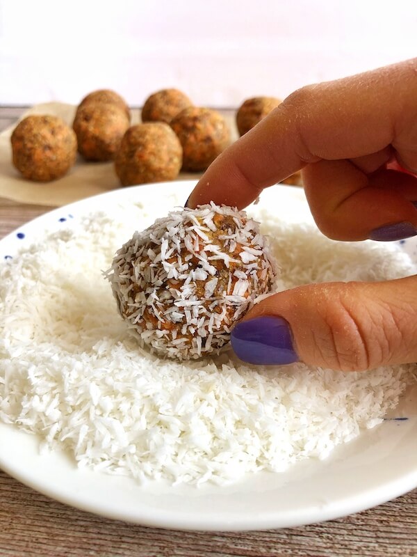 rolling carrot cake energy balls in shredded coconut