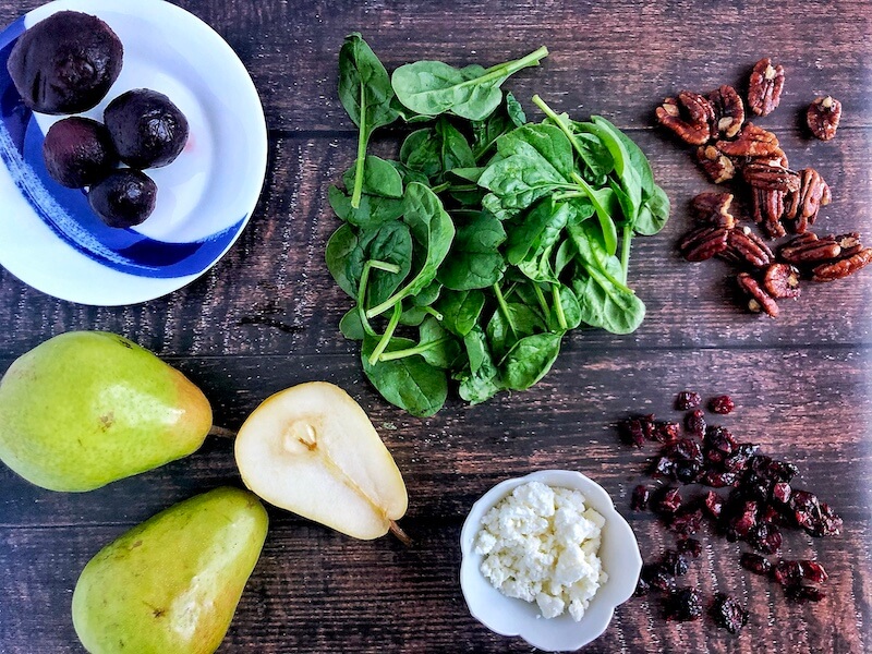 Ingredients to make a spinach salad with pear, goat cheese, and pecans