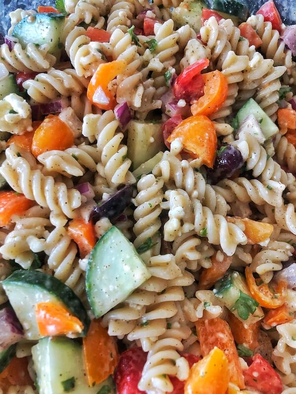 close up pasta salad with tomato, cucumber, pepper, feta and olives